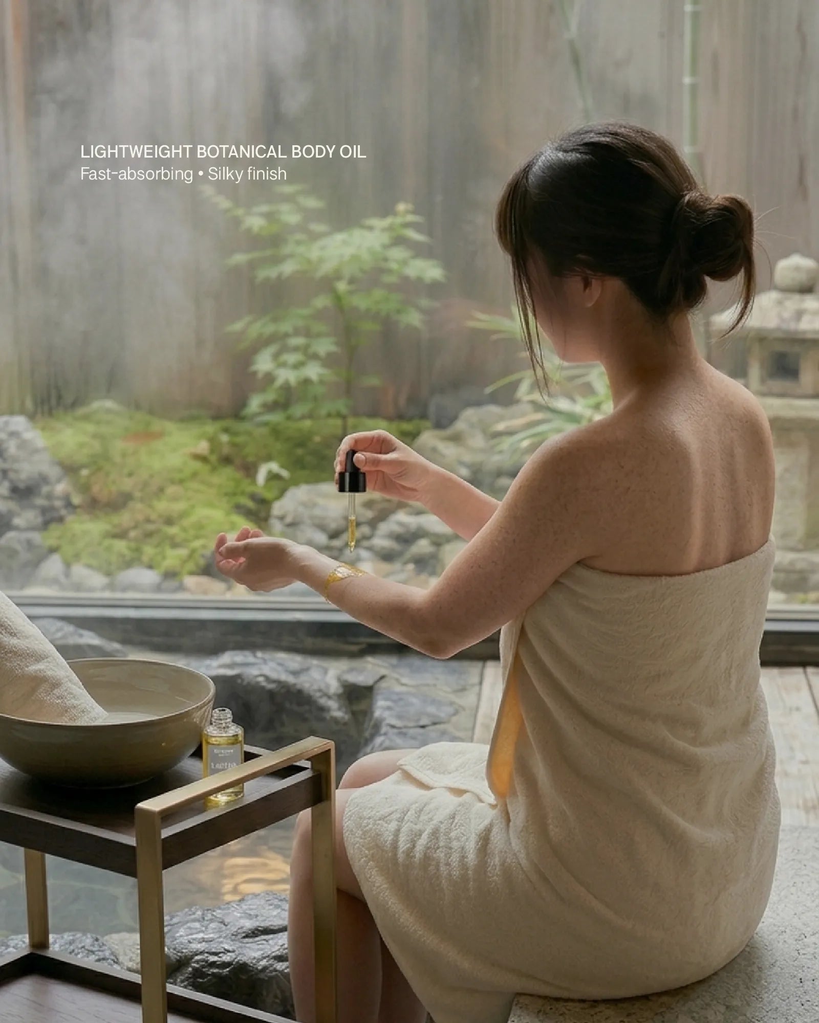 Woman in a towel applying oil by a hot spring with a garden view