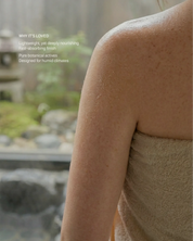 Woman wearing a towel with text about body oil benefits on a blurred natural background