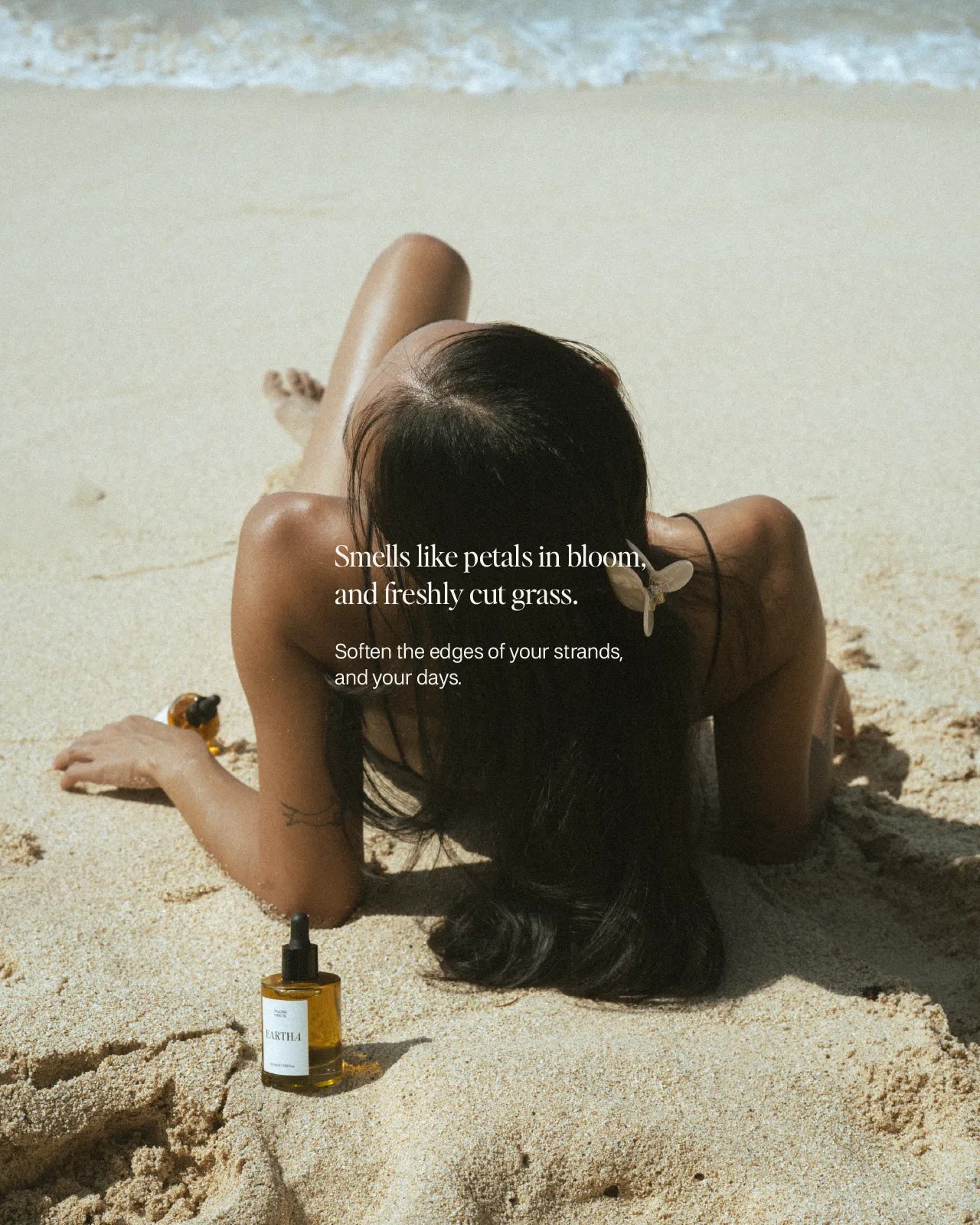 Person sitting on a beach with a bottle of hair oil, text overlay about scent and feeling.