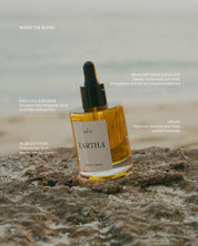 Eartha hair oil bottle on a rocky surface with text about ingredients