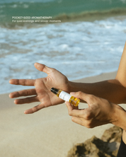 Person applying an essential oil roll-on to her palm on a beach
