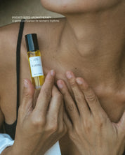 Close-up of a woman holding an Aurora essential oil roll-on against their skin.