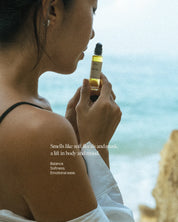 Woman holding a bottle of essential oil roll-on a scenic background