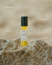 Aurora essential oil roll-on against a blurred natural background.