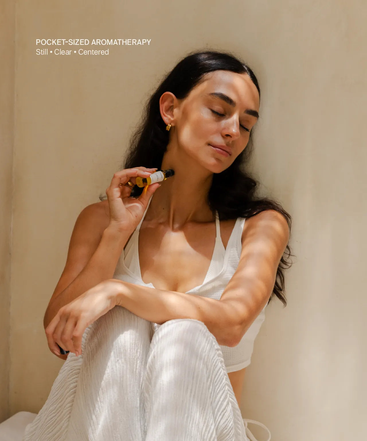 Woman holding a Quiet Moments essential oil roll-on with a relaxed vibe