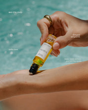 Hand applying an essential oil roll-on to skin by the pool, with key ingredients write up