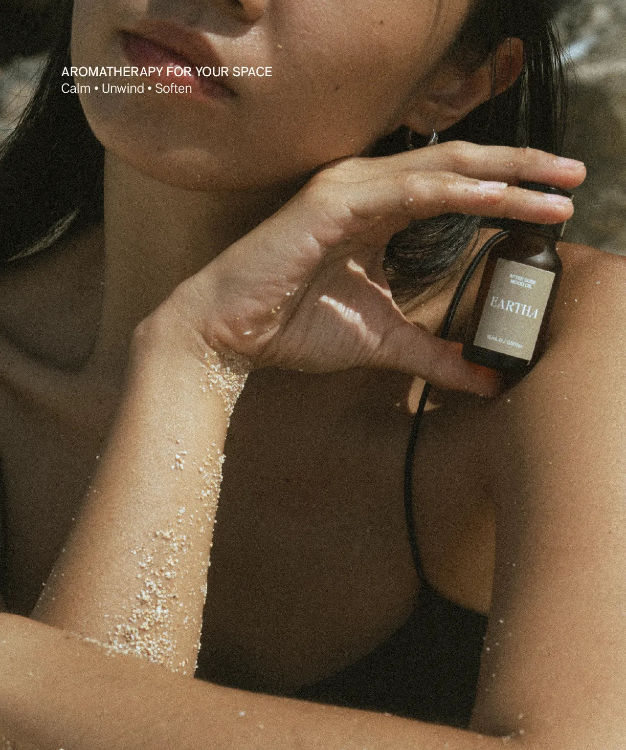 Woman holding a bottle of Eartha mood oil near their face with text 'Aromatherapy for Your Space' above.