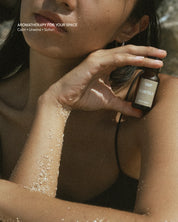 Woman holding a bottle of Eartha mood oil near their face with text 'Aromatherapy for Your Space' above.