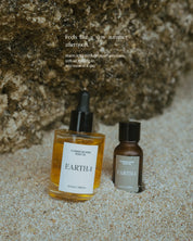 A body oil and essential oil on sand with a rock background