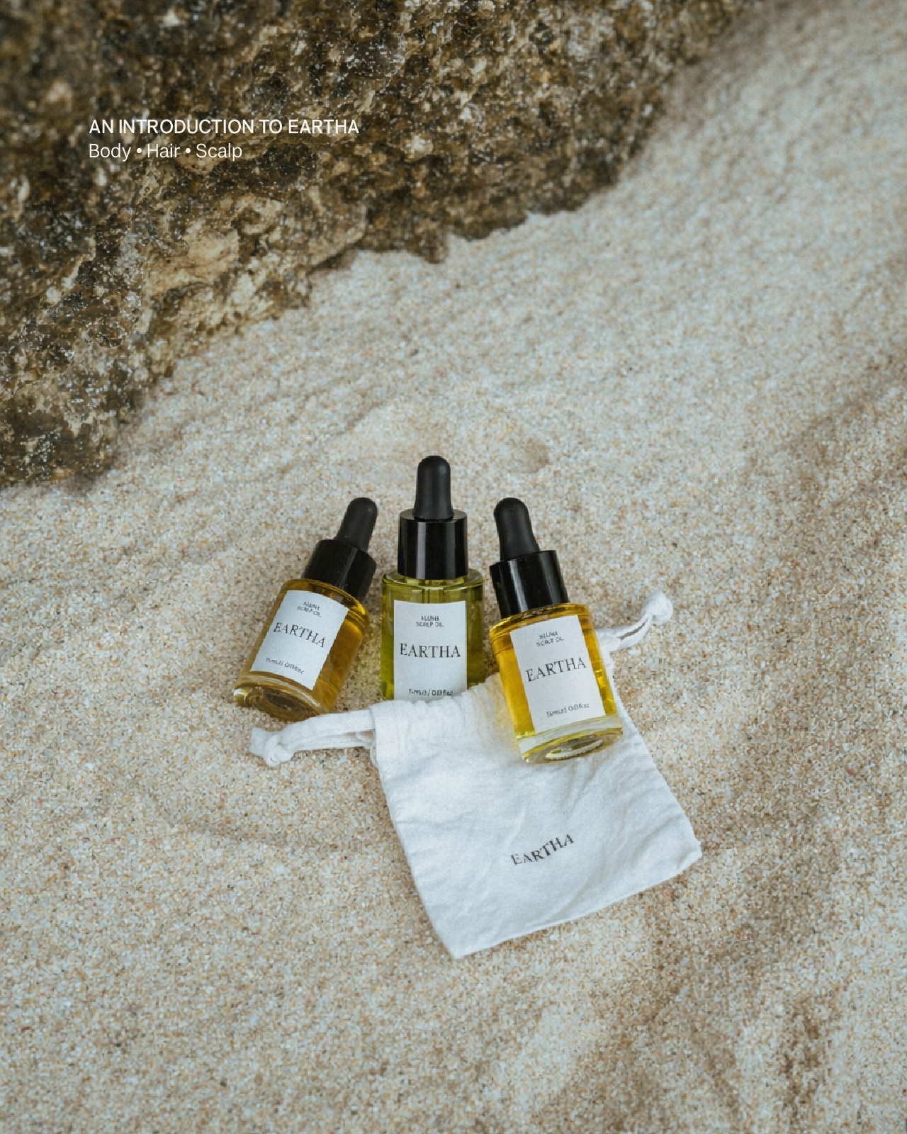 Three dropper bottles with a white pouch on a textured stone surface, featuring the brand 'Eartha'.